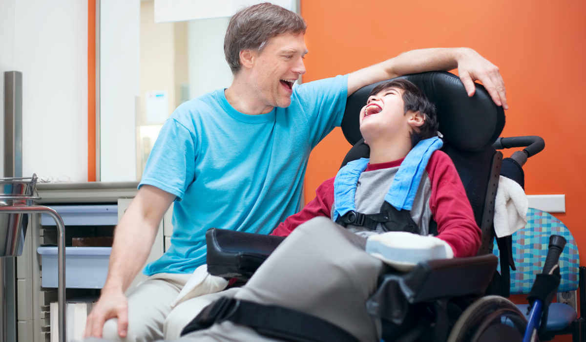 Батько посміхається своїй дитині з інвалідністю