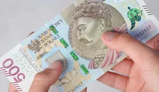 Українка тримає в руках грошову допомогу в Польщі