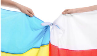 Две руки держат украинский и польский флаг связаные вместе-RU