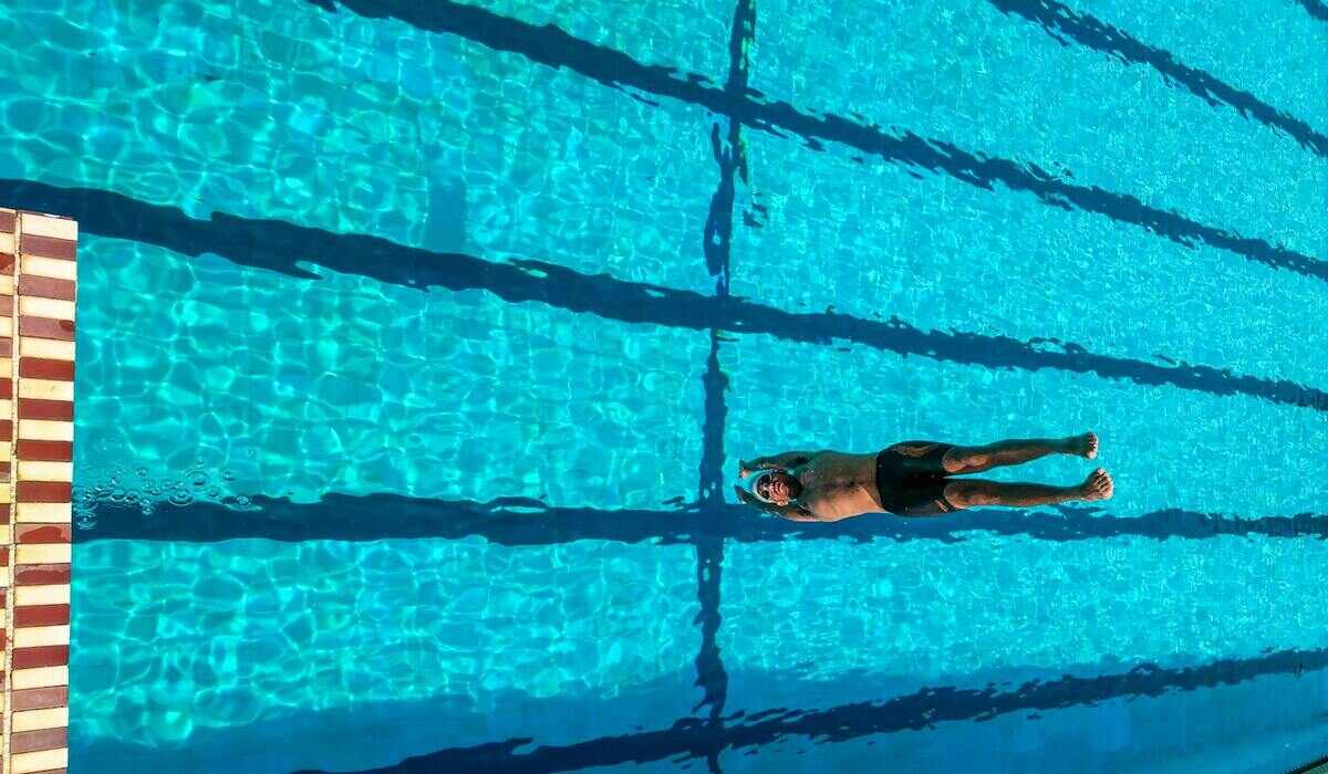 Чоловік плаває у спортивному басейні