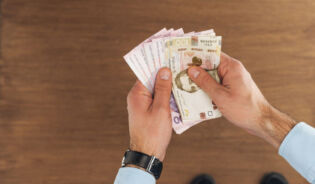 Mężczyzna trzymający pensje minimalną w hrywnach