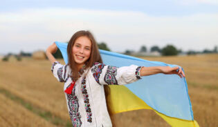 Dziewczyna trzymająca flagę Ukrainy na polu pszenicy