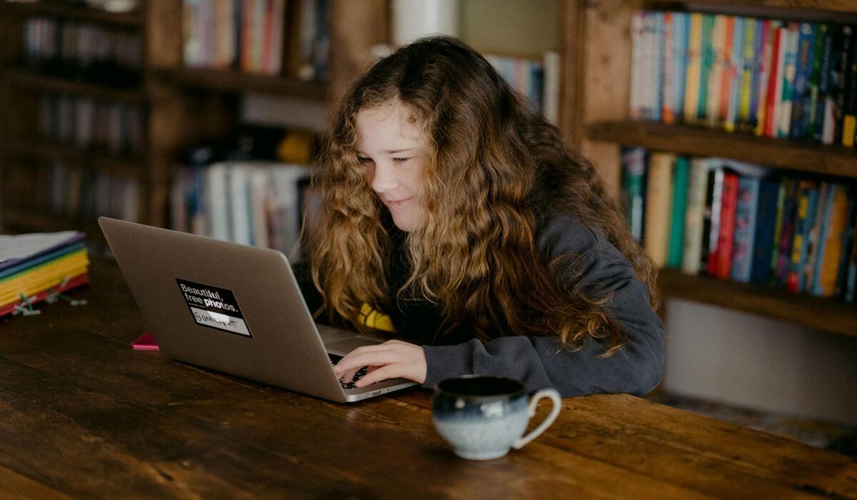 Dziewczyna siedzi przy laptopie w czarnej bluzie