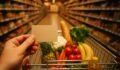 Wozek z zakupami spozywczymi w hipermarkecie i karta lojalnosciowa w dloni klienta