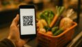 Klient skanuje kod QR karty lojalnosciowej w telefonie przy kasie sklepu spozywczego